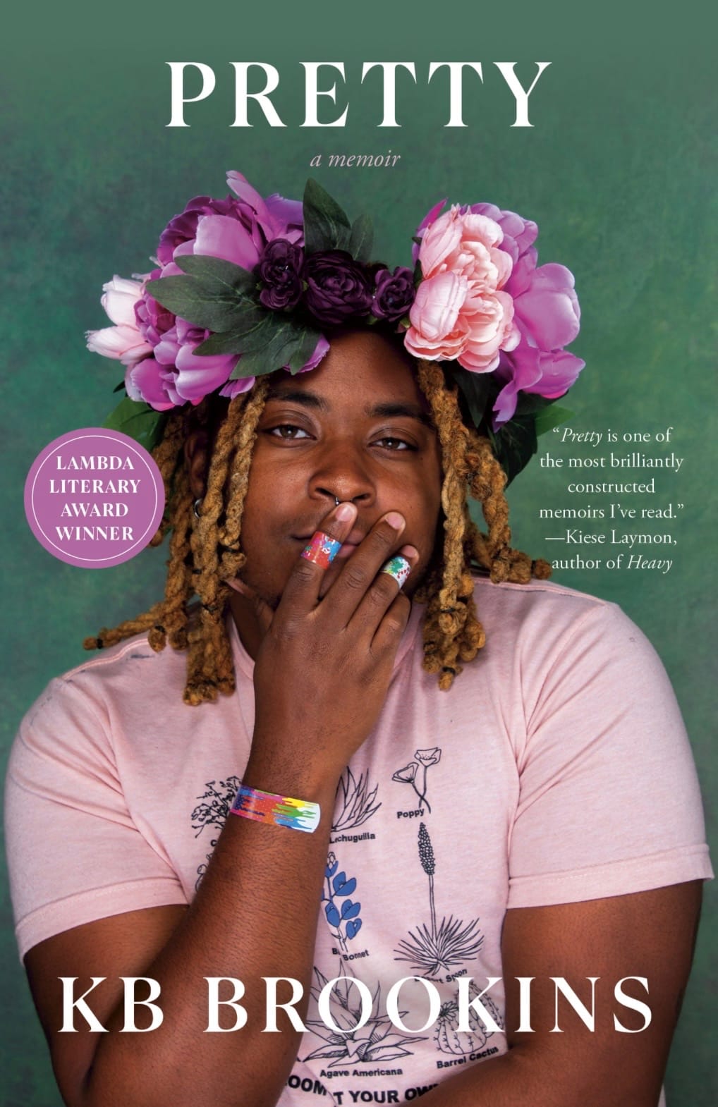KB, a black person with brown skin and blond locs, looks at the camera with one of their hands covering their mouth. their hands and arms have band-aids over them, and they have a purple and pink flower crown on them. atop the image reads “PRETTY” and “KB Brookins”