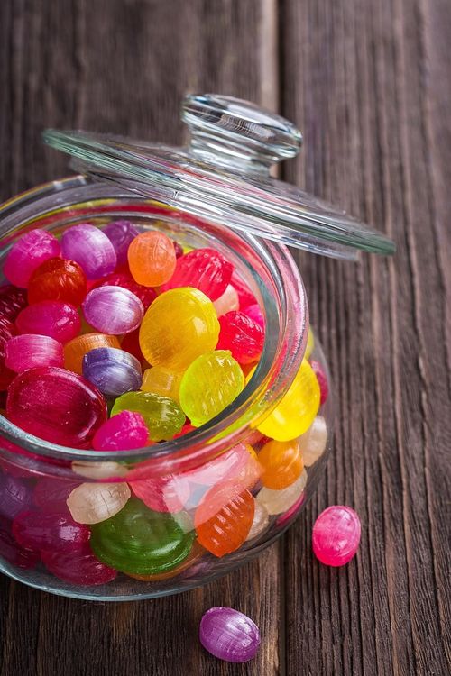 A jar of colourful boiled sweets with the lid off.
