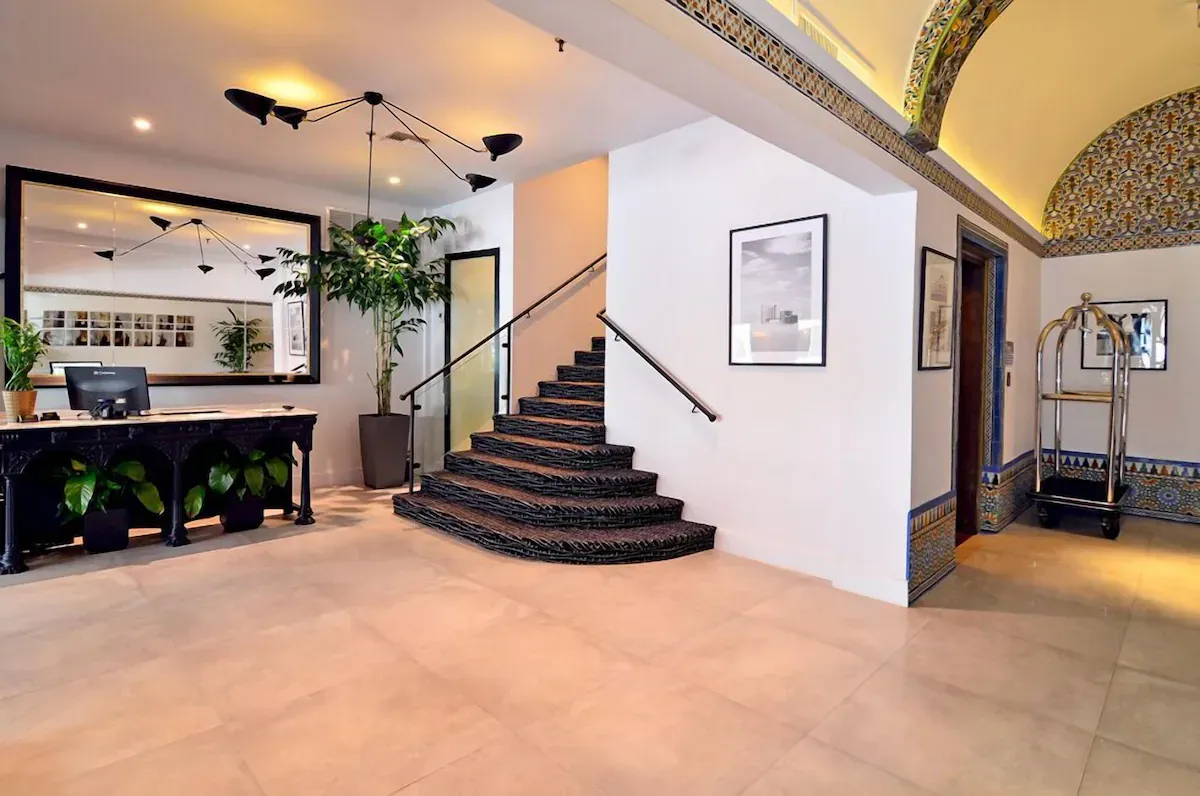 Lobby of Hotel St. Michel, a boutique hotel in Coral Gables, featuring a vintage staircase, antique furnishings, and European-style historic charm.
