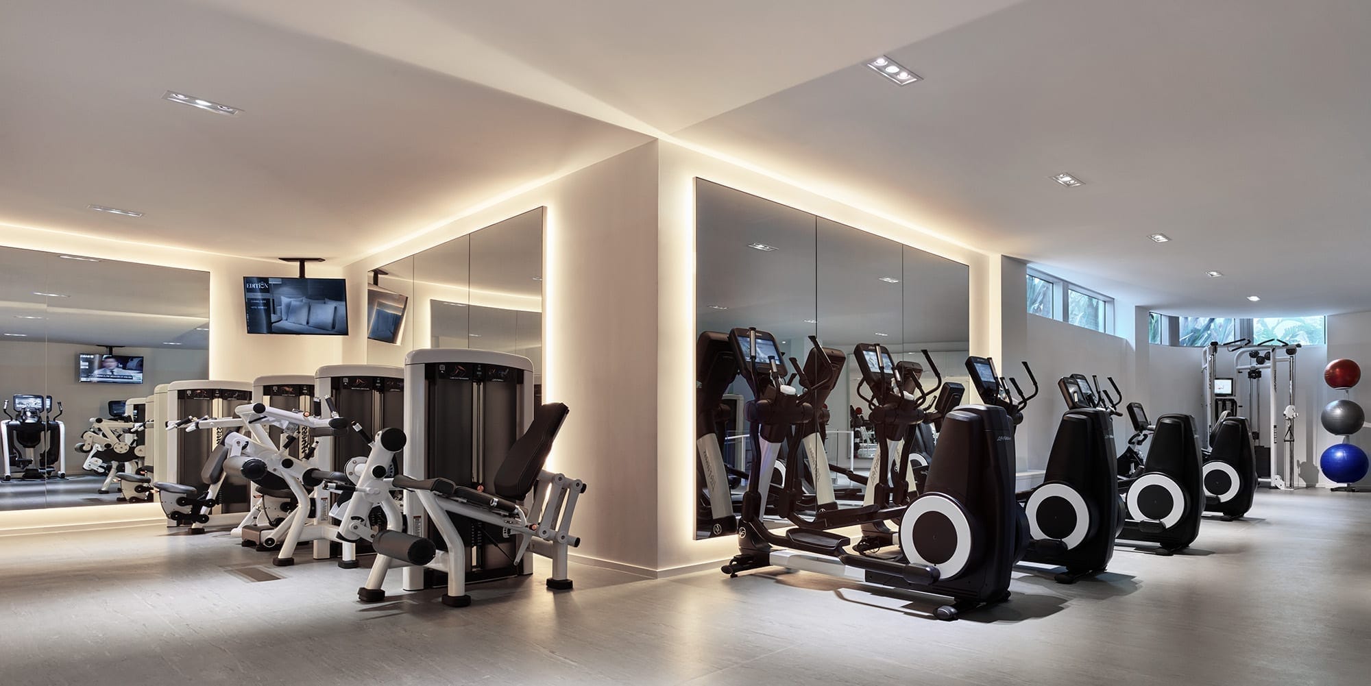 The Miami Beach EDITION fitness center with cardio machines, strength equipment, and mirrored walls.