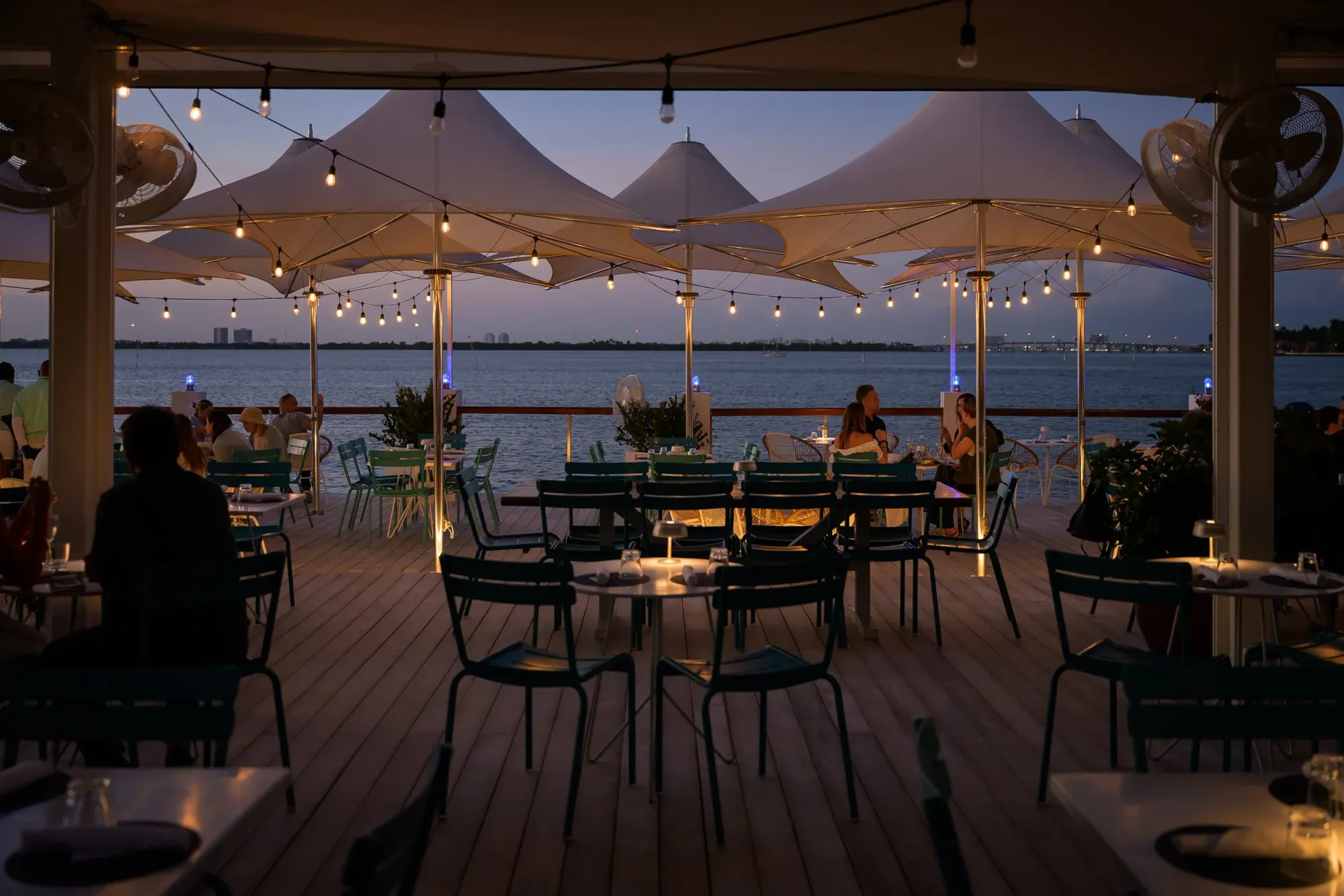 Lido Bayside Grill at The Standard Spa, Miami Beach—waterfront patio dining at dusk with string lights, white canopies, and Biscayne Bay views.