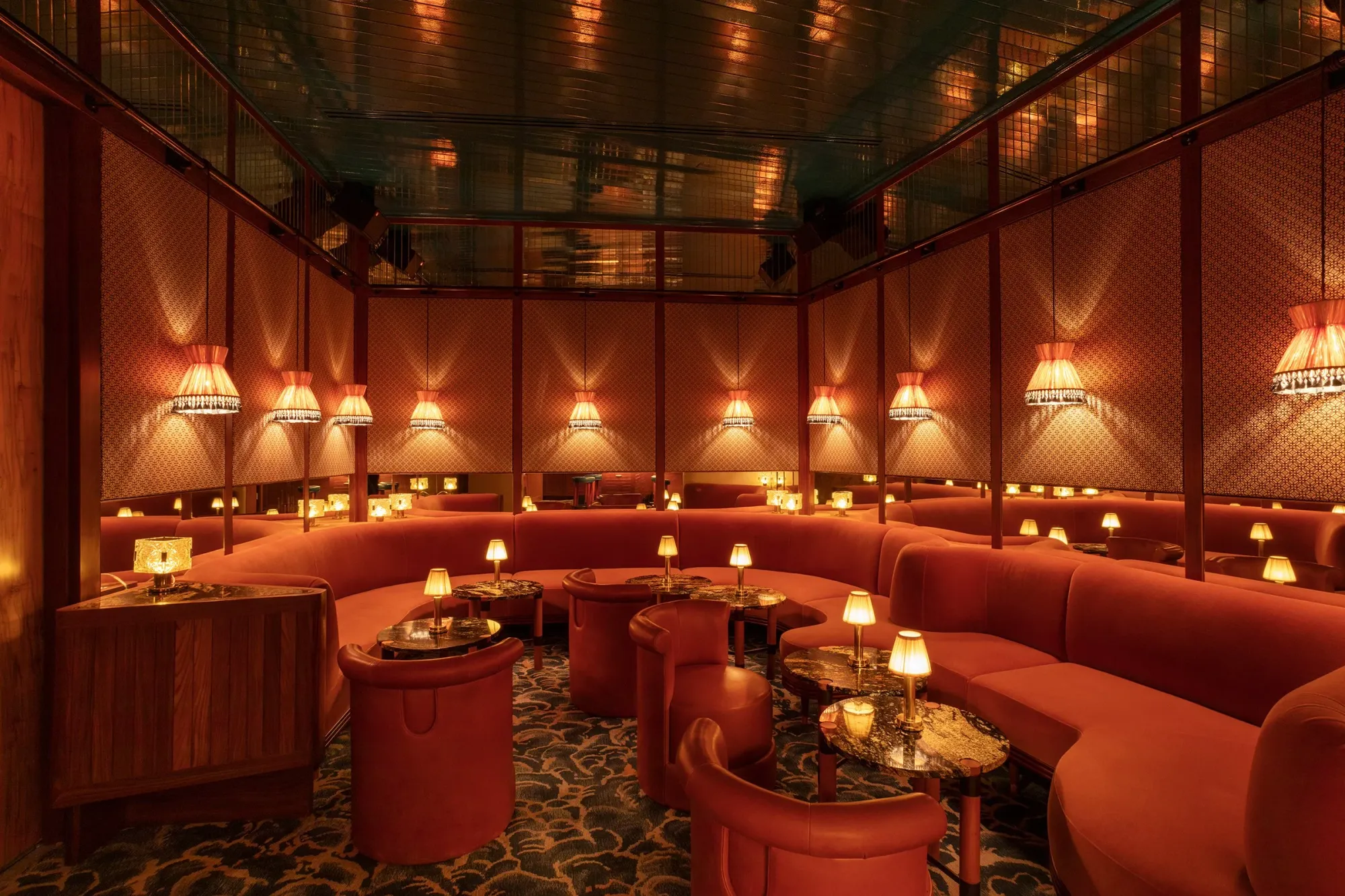 Monterrey Bar at The Standard Spa, Miami Beach—dimly lit lounge with coral velvet banquettes, marble tables, vintage lamps, and mirrored walls.