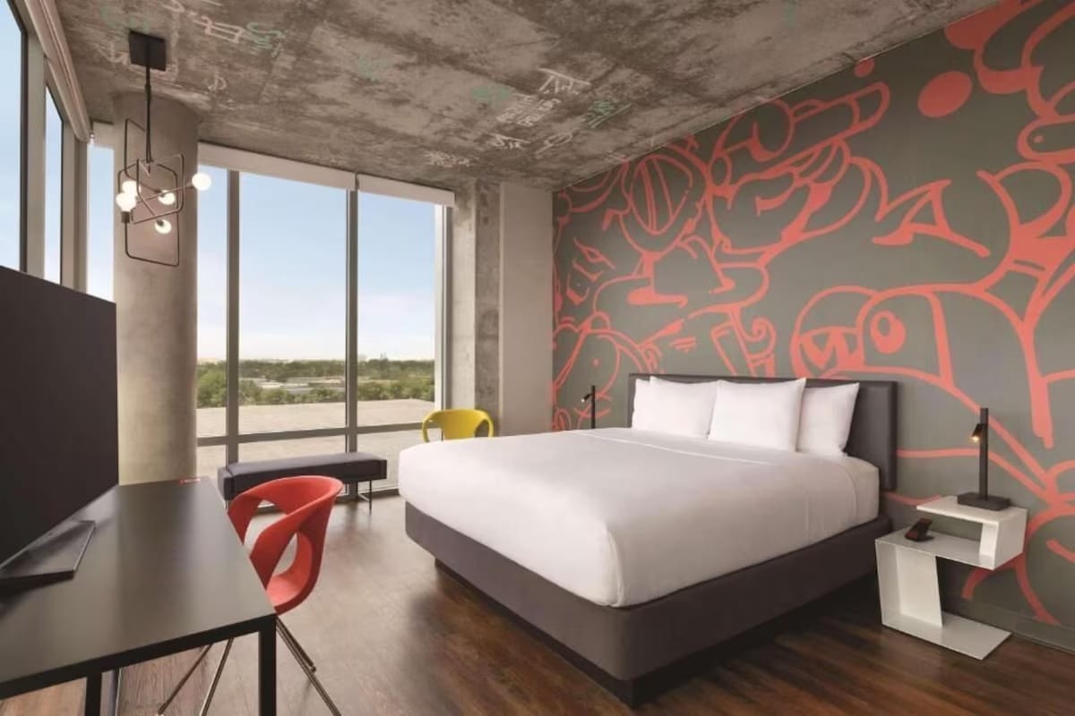 Guest room at Kompose Boutique Hotel Miami Airport with mural wall, king bed, and in-room workspace