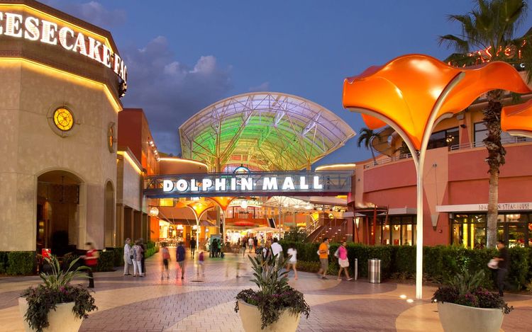 Entrada principal de Dolphin Mall en Miami de noche, centro comercial cerca de los mejores hoteles en Doral