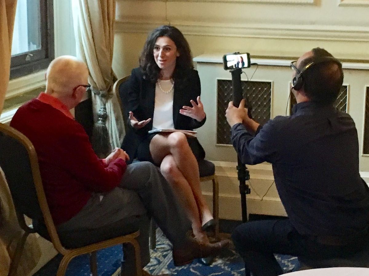 A dark-haired speaker gestures mid-answer at a marcomms masterclass as a crew member films her on a phone.