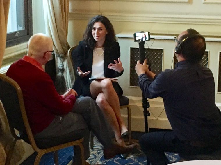 A dark-haired speaker gestures mid-answer at a marcomms masterclass as a crew member films her on a phone.
