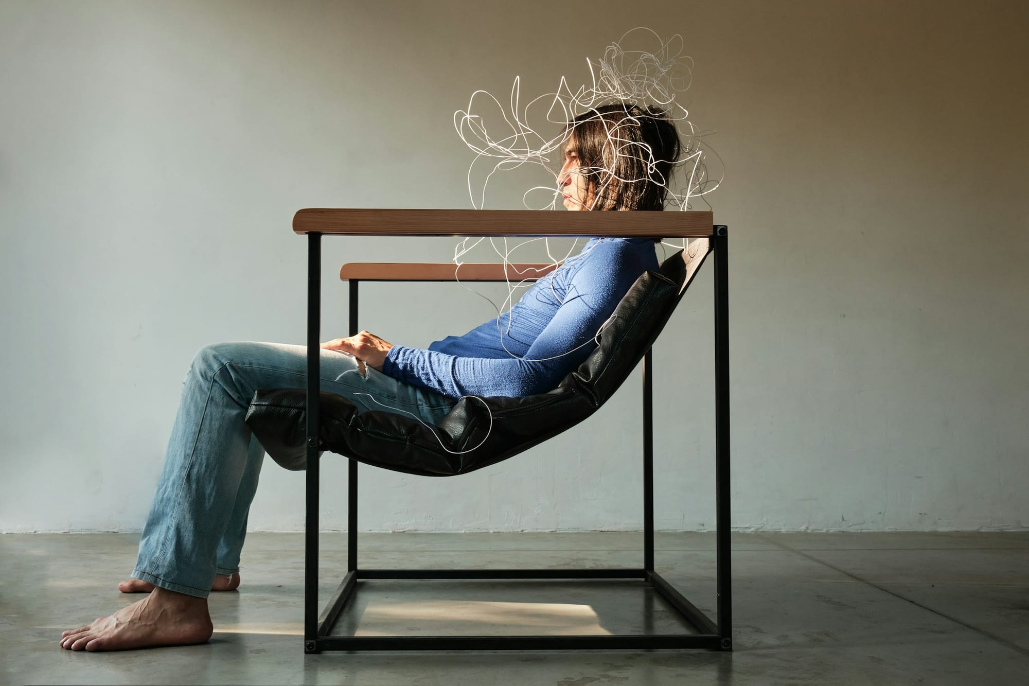 slumped in a chair with illustrated scribbles swirling around her head, visualizing mental overwhelm
