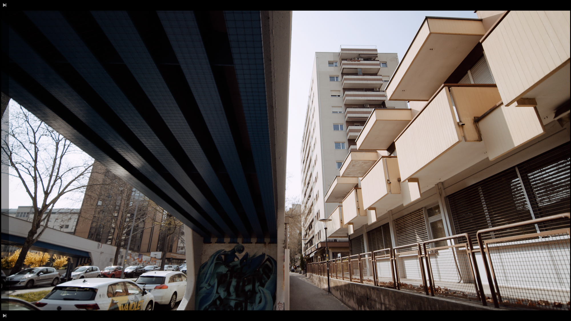 Una passerella pedonale accanto a un palazzo, ripresi dal basso.
