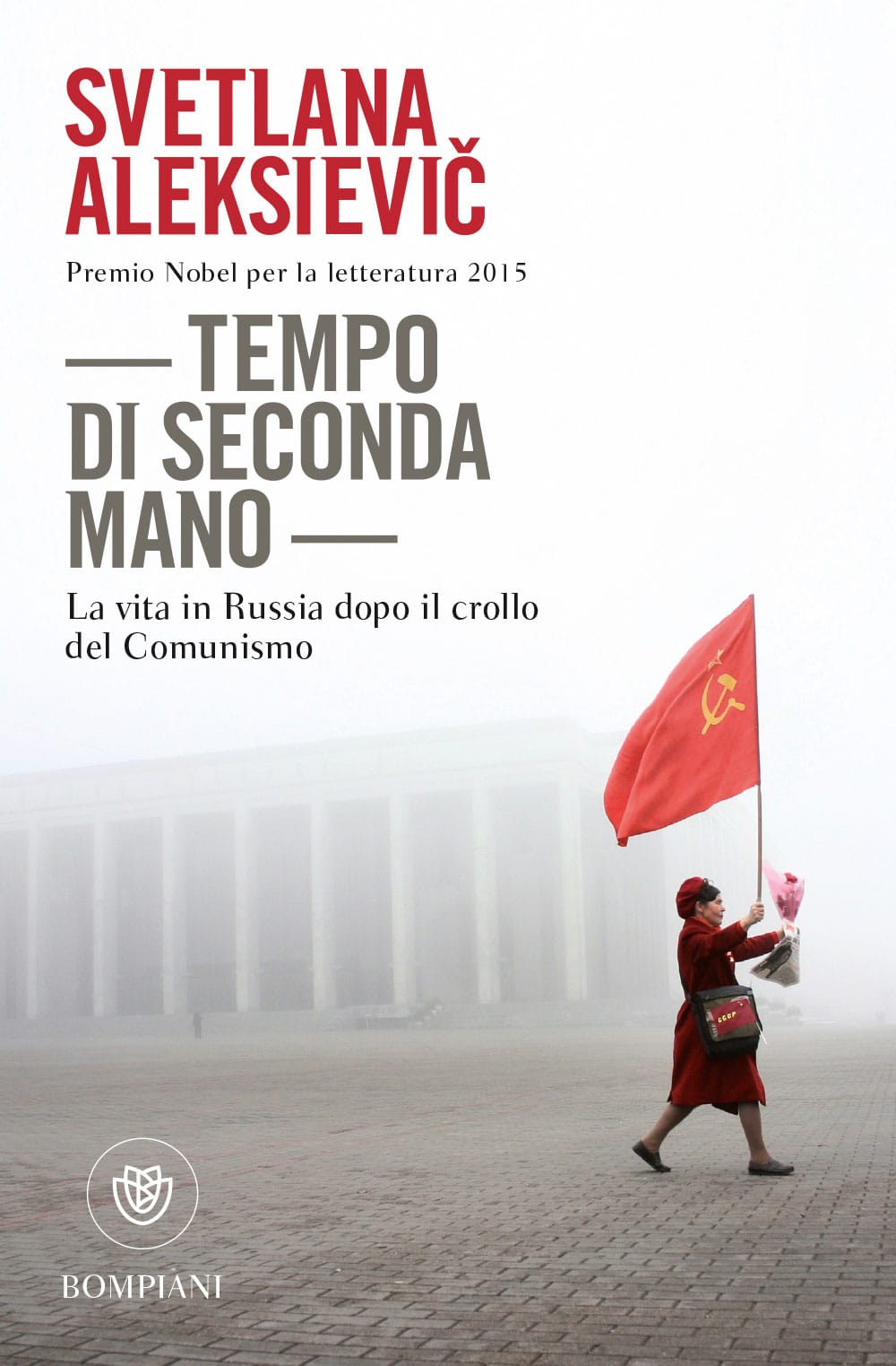Una donna, vestita di rosso, cammina tenendo in mano una bandiera sovietca e un mazzo di fiori.