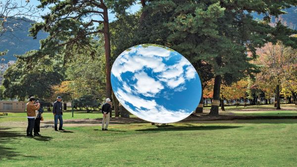 Uno specchio orientato verso il cielo riflette le nuvole al centro di un parco. Sky Mirror, installazione di Anish Kapoor.
