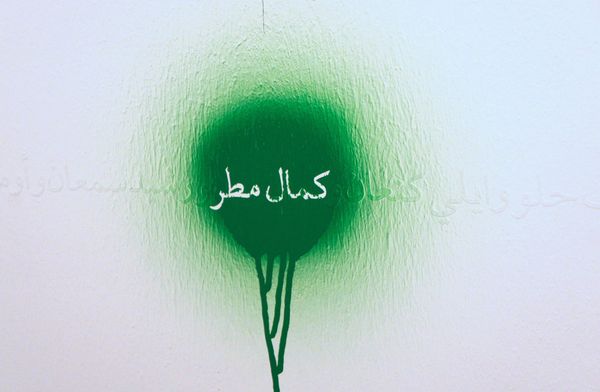 Macchia bianca su un muro verde. All'interno della macchina c'è una scritta in arabo.