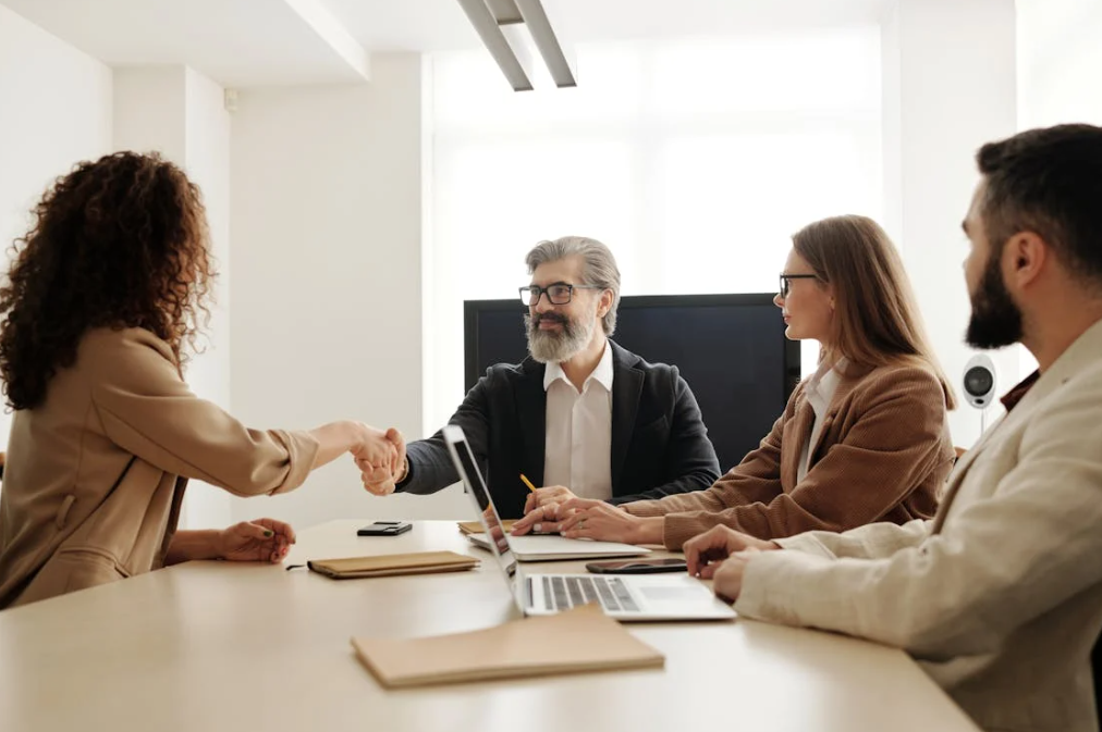 Business professionals in a meeting shaking hands across a table.