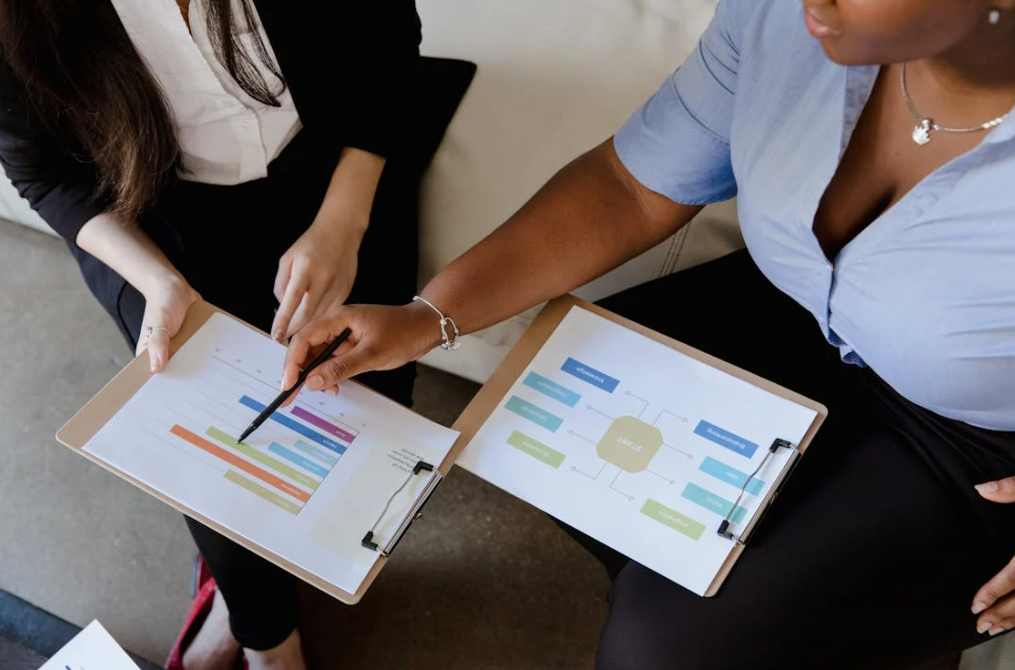 Two professionals reviewing charts on clipboards.