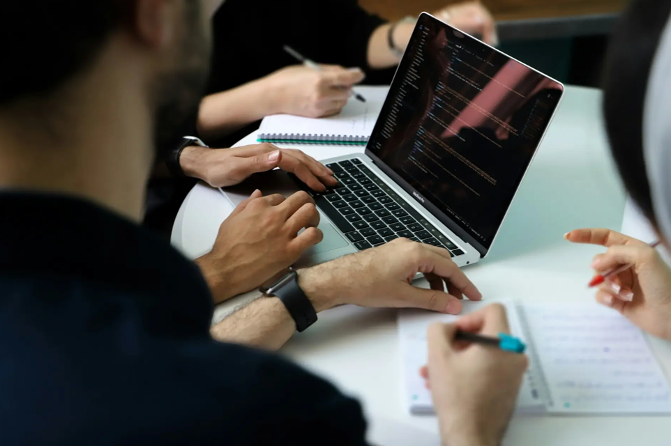 Team reviewing data and notes together on a laptop during an analysis meeting.
