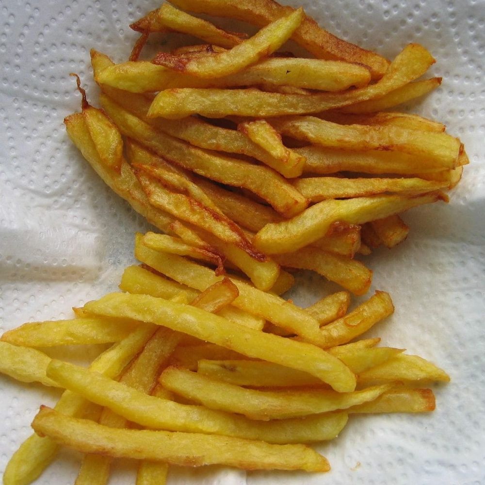 Golden homemade French fries draining on paper towel