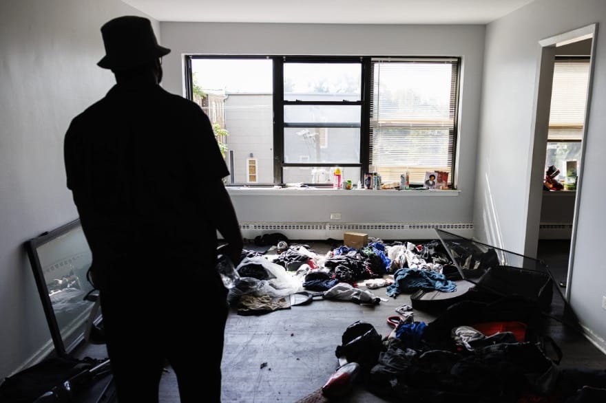 A photo of a man looking at a mess in his apartment
