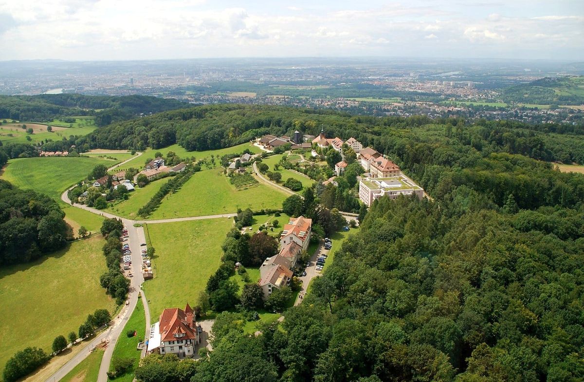 Blick von oben auf St. Chrischona mit Kirche, Siedlung und umgebenden Feldern