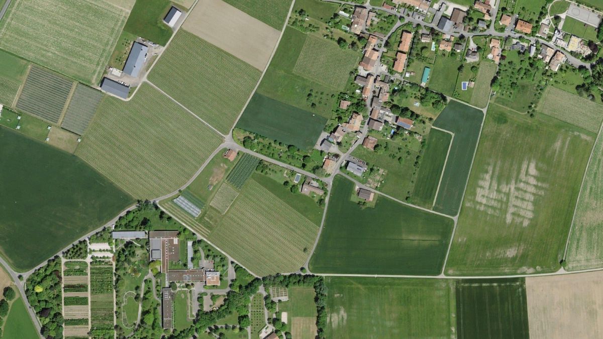 Luftbild von Lullier mit Dorf, Feldern und einem Teil der Ausbildungsanlagen