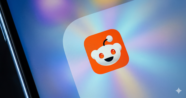 A close-up shot of the orange Reddit app icon on a smartphone screen, featuring a slightly modified background with soft, colorful light bursts.