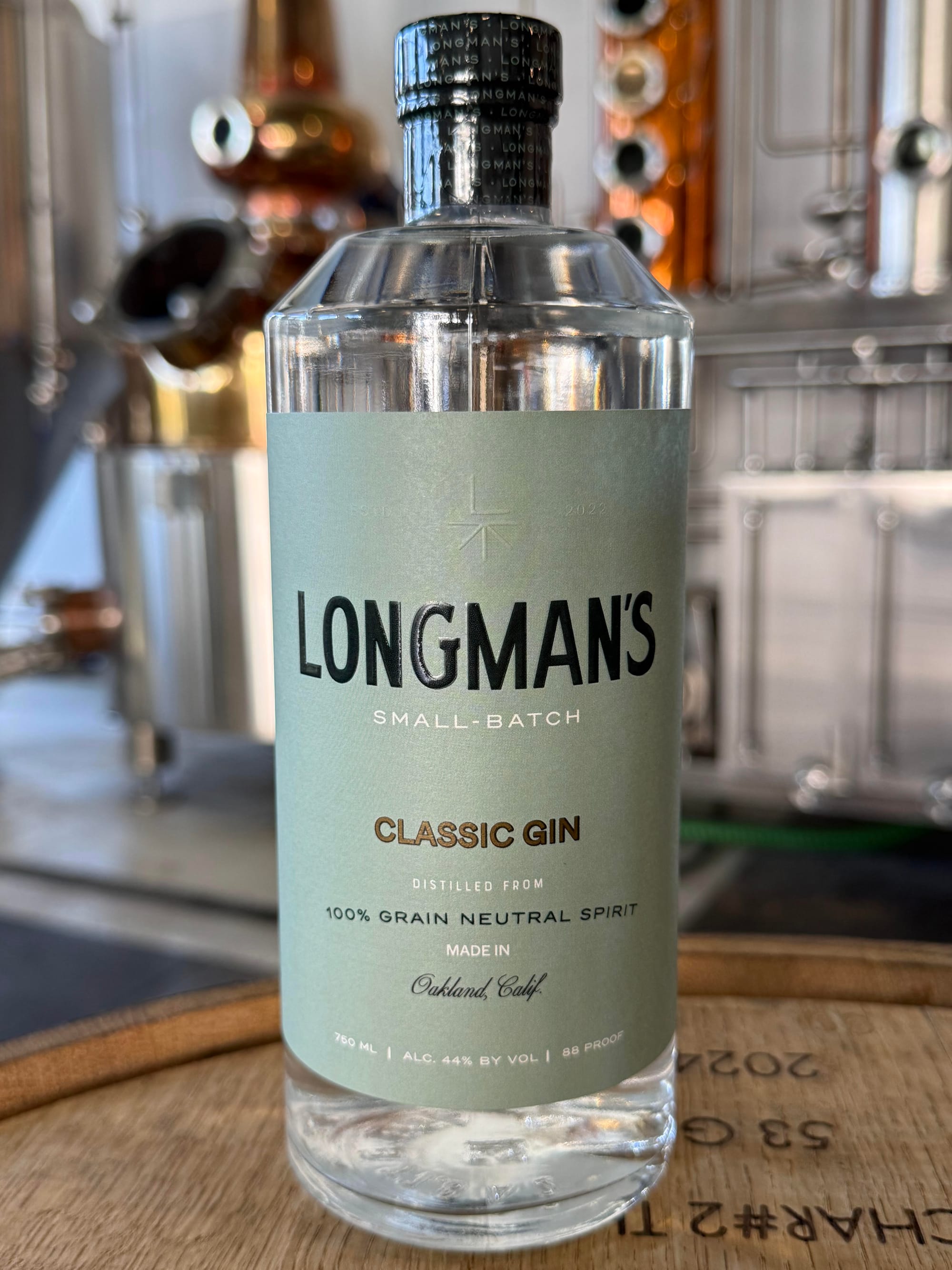 A bottle of Longman's Classic Gin positioned on a barrel at the P&W Distillery.