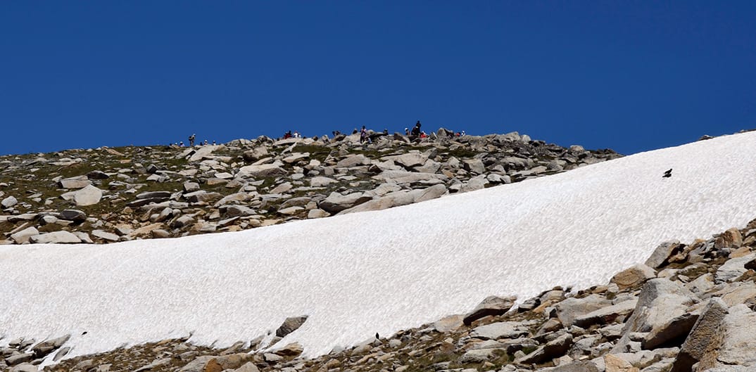 In early summer you usually find a snow drift below the summit. The people at the top are on the summit.