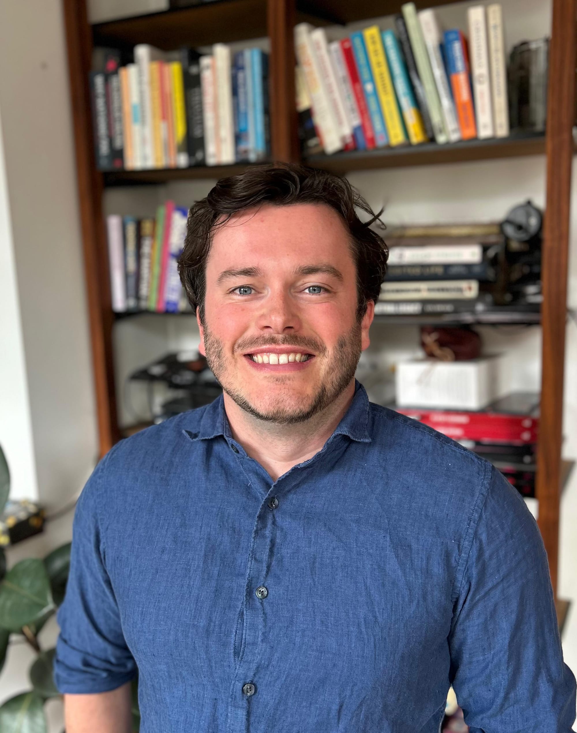 Rhys Davies standing in front of a bookcase smiling.