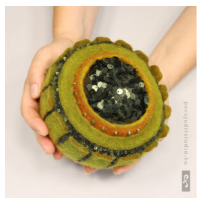 Tovad behållare i grönt med lock av intovade paljetter och dekor på sidorna. Av Judit Pócs.