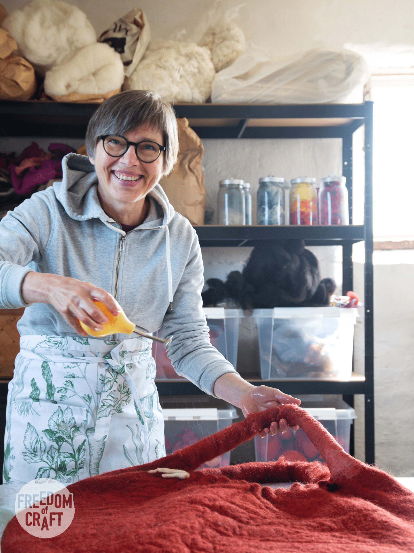 Woman smiling at the camera. She is working on her felt project, holding a water sprayer.
<p>En kvinna ler mot kameran, medan hon arbetar på sitt filtningsprojekt. Hon håller i en tryckflaska med vatten." class="wp-image-1182"><figcaption class=