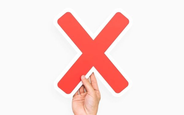 Mano che solleva un grande simbolo di X rossa, a simboleggiare un giudizio negativo o una critica ricevuta.