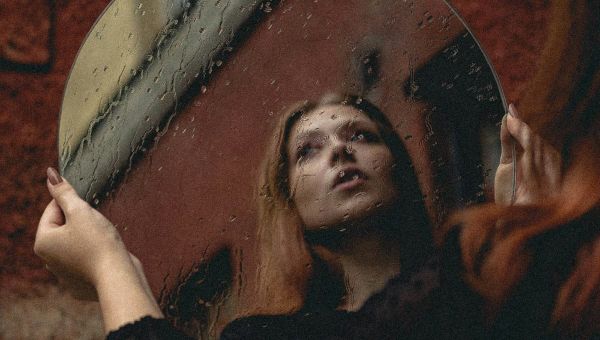 Persona che si guarda allo specchio, metafora della sindrome dell'impostore e del dubbio su se stessi