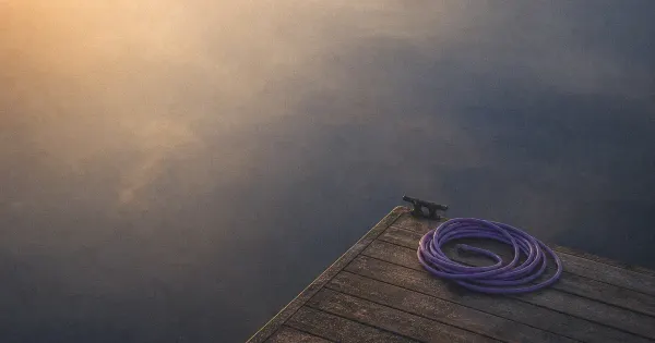 Lanterna spenta su un molo, accanto a una finestra con scie di pioggia, nella nebbia che si dirada — migliorare…