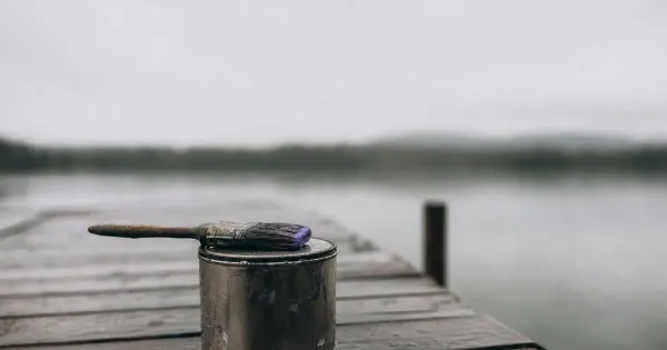 Pennello su barattolo di vernice chiuso, su un molo sull'acqua calma, dopo la pioggia, mindfulness nell'era digitale