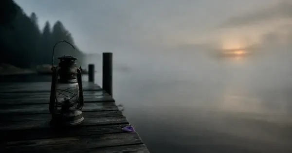 Lanterna spenta su un molo, su un molo sull'acqua calma, nella nebbia che si dirada, segreti psicologici carisma
