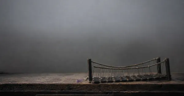 Asse di ponte di corde nella nebbia, su una scrivania di legno consumata, nella nebbia che si dirada, trappola dell'ego…