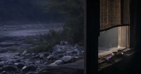 Tenda a mezza altezza e polvere nella luce, su una riva di pietre lisce, dopo la pioggia, trascendenza nella vita quotidiana