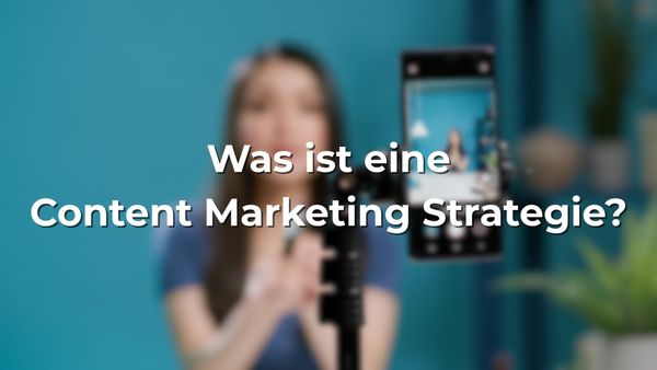 Frau nimmt Video mit Smartphone auf, unscharfer Hintergrund, Text im Bild: „Was ist eine Content Marketing Strategie?“