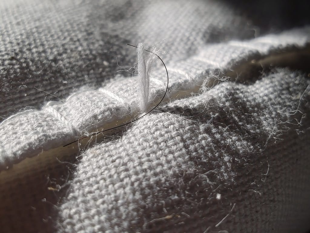 A strand of hair snagged on the rough texture of a cotton pillowcase