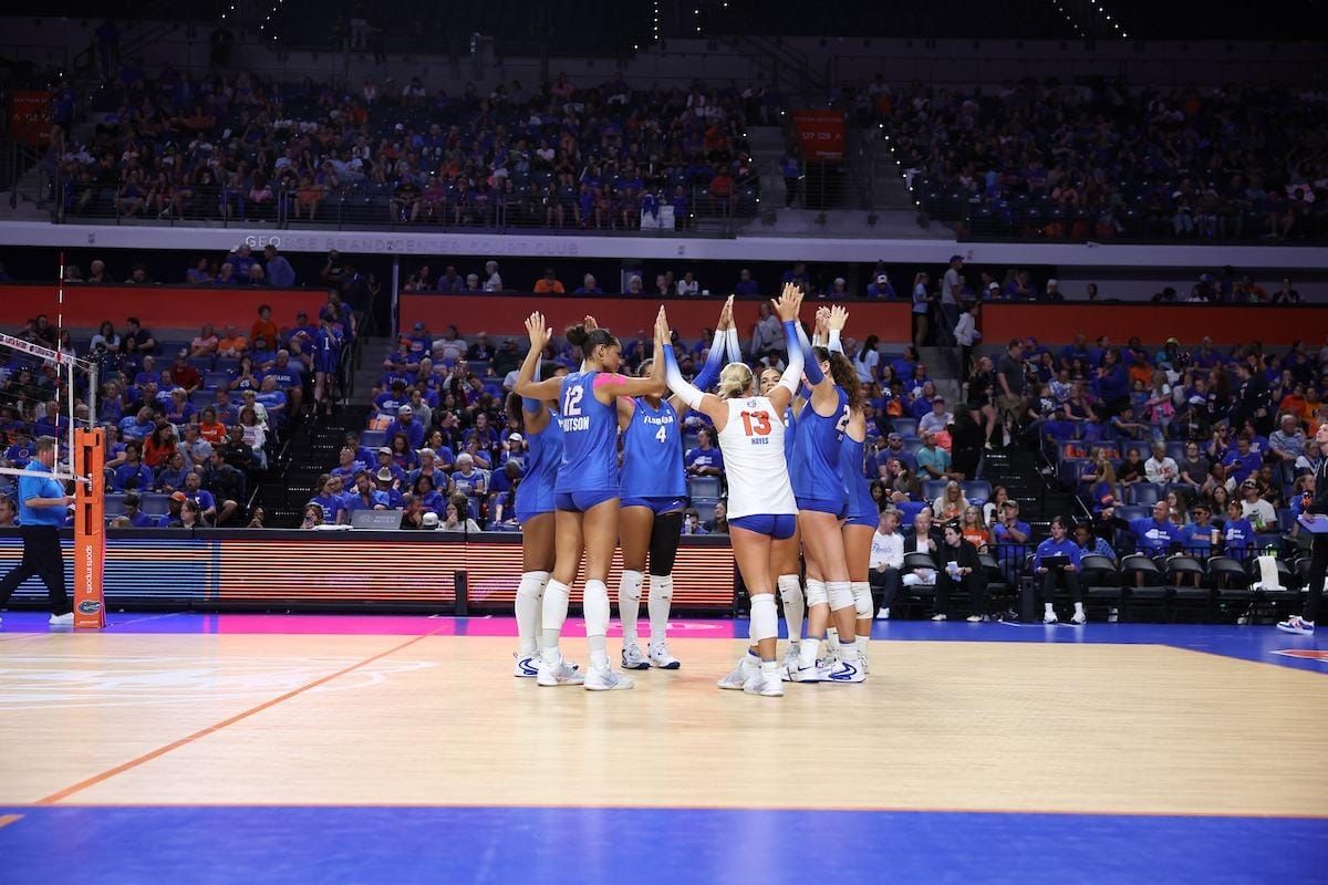 Florida volleyball players celebrate together on the court in front of a home crowd