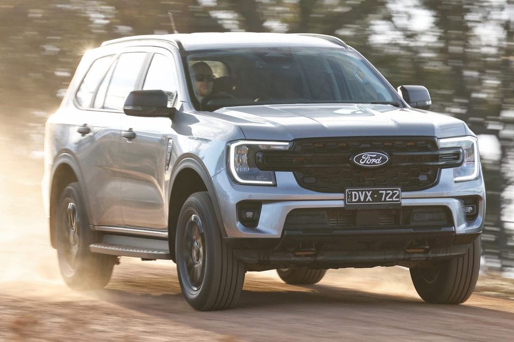 Silver Ford Everest SUV driving along a dusty gravel road