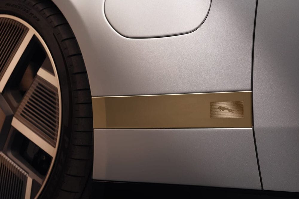 Close-up of a brass-coloured trim strip with an embossed Jaguar leaper badge behind the front wheel