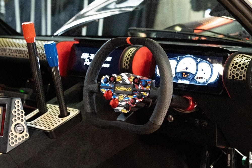 Porsche 911 race-style cockpit with two upright levers, a button-covered steering wheel and a digital dash