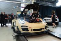 Sandy Taupe Porsche 911 wide-body with its front bonnet open revealing a twin-turbo V8