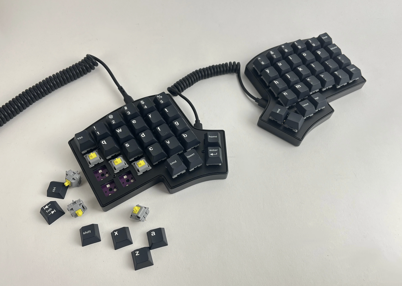 The Iris SE columnar stagger split mechanical keyboard, built with its machined aluminum tray with the Durock Sunflower POM T1 Tactile switches topped with the Tuxergo keycaps and connected with a coiled USB-C cable.