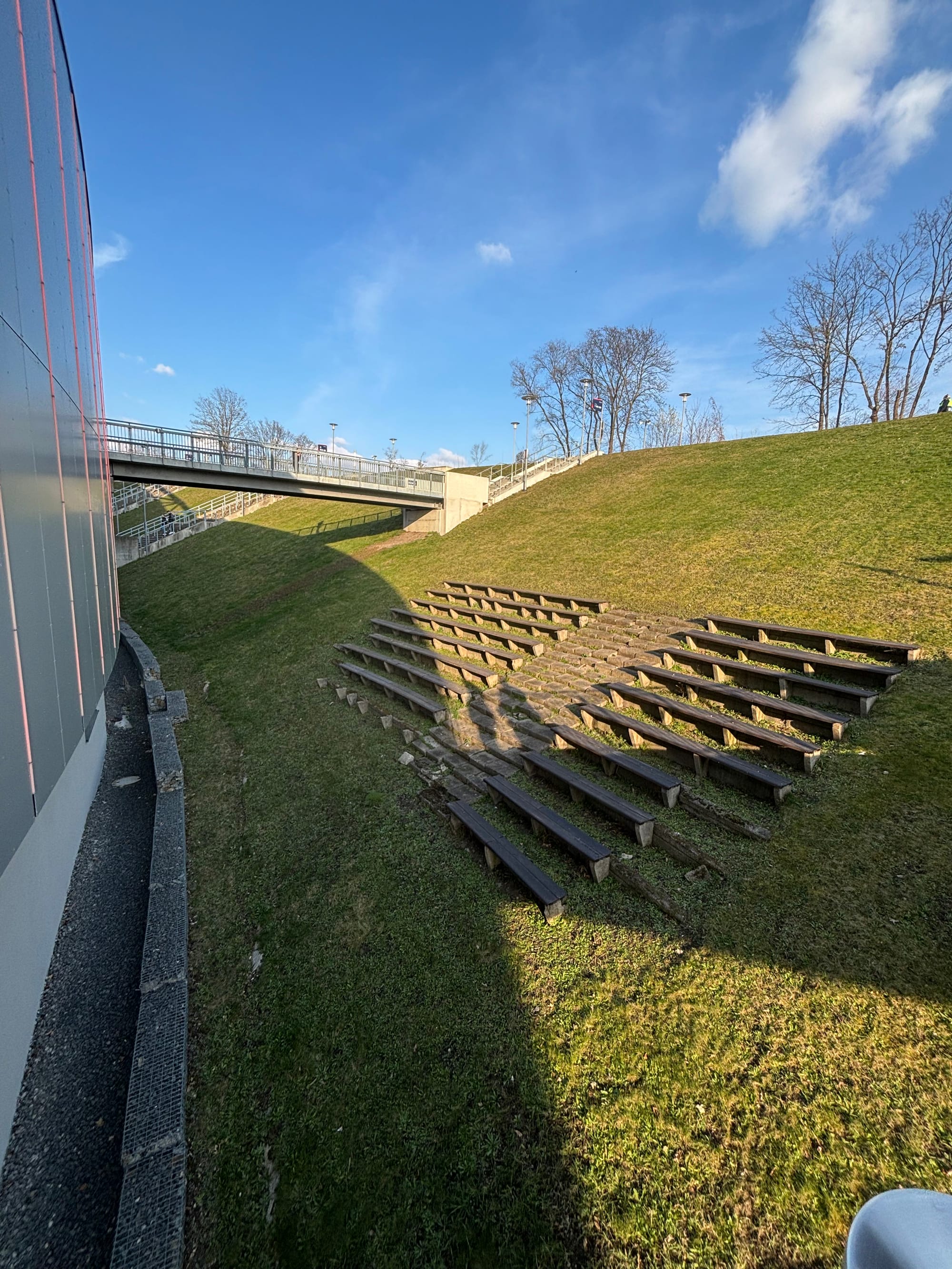 The old, preserved wooden seating of Zentralstadium on a hillside, facing the wall of RB Arena