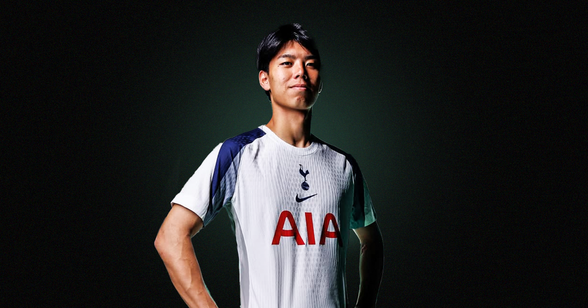 Kota Takai stood in a white-and-navy Tottenham Hotspur shirt, stood in front of a dark background with a green glow behind him