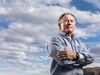C3 AI chairman and CEO Thomas Siebel stands against a cloudy skyline.