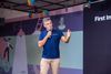 Freshworks CEO Dennis Woodside speaks on stage at a recent event wearing a blue golf shirt and khakis.