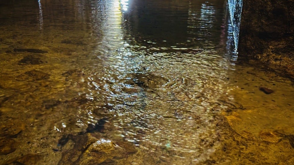Water flows from below through fissures, inside the Roman Galleries in Lisbon
