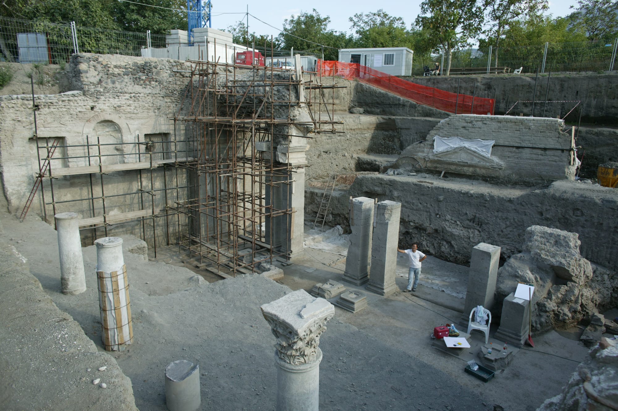An archaeologist stands next to a pillar to show the magnitude of the construction.