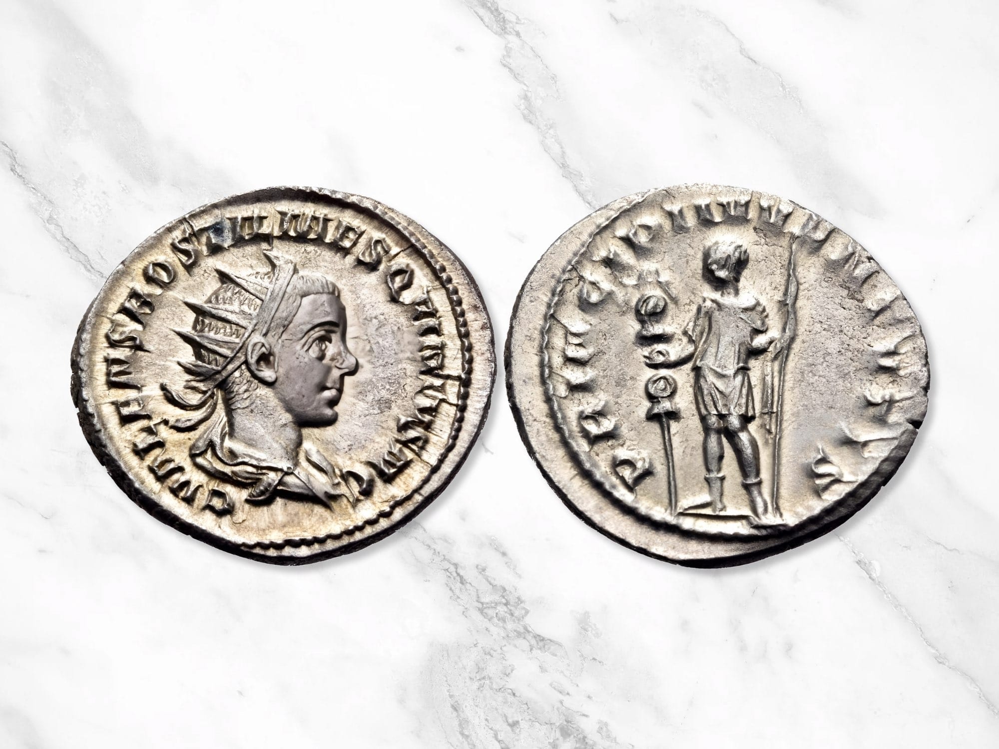 A Roman silver Antoninianus coin showing Hostilian as Caesar, and standing to left, holding standard in right hand and transverse scepter in left